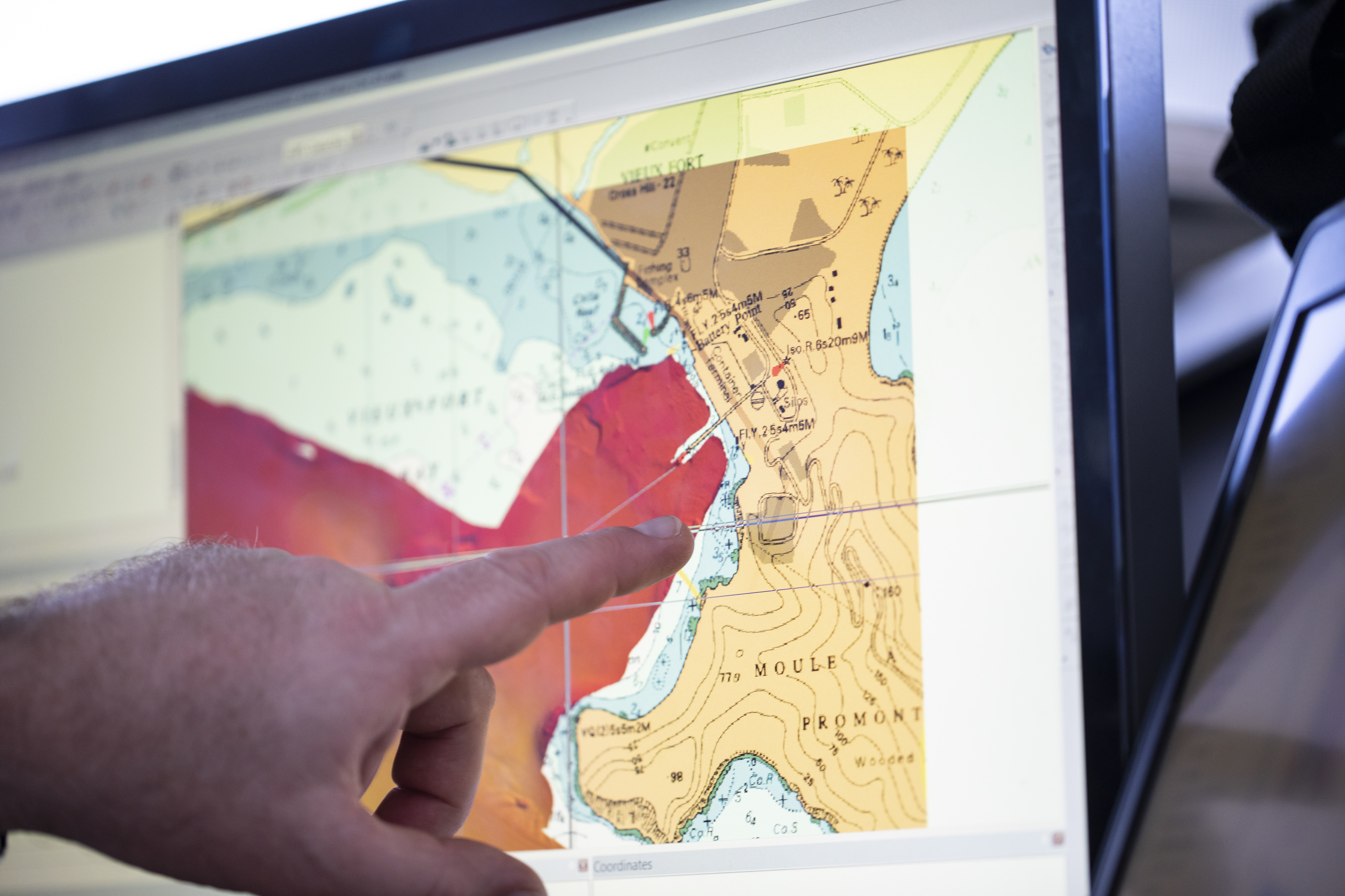 Person pointing at a screen with UKHO data discplayed
