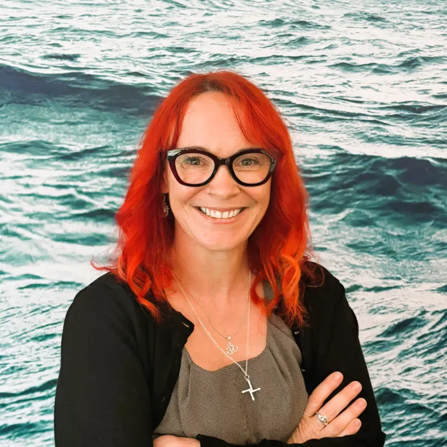Woman with red hair smiling against a blue background
