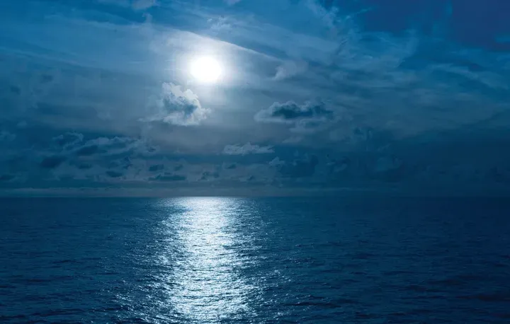 Moon casting reflection over the ocean at night