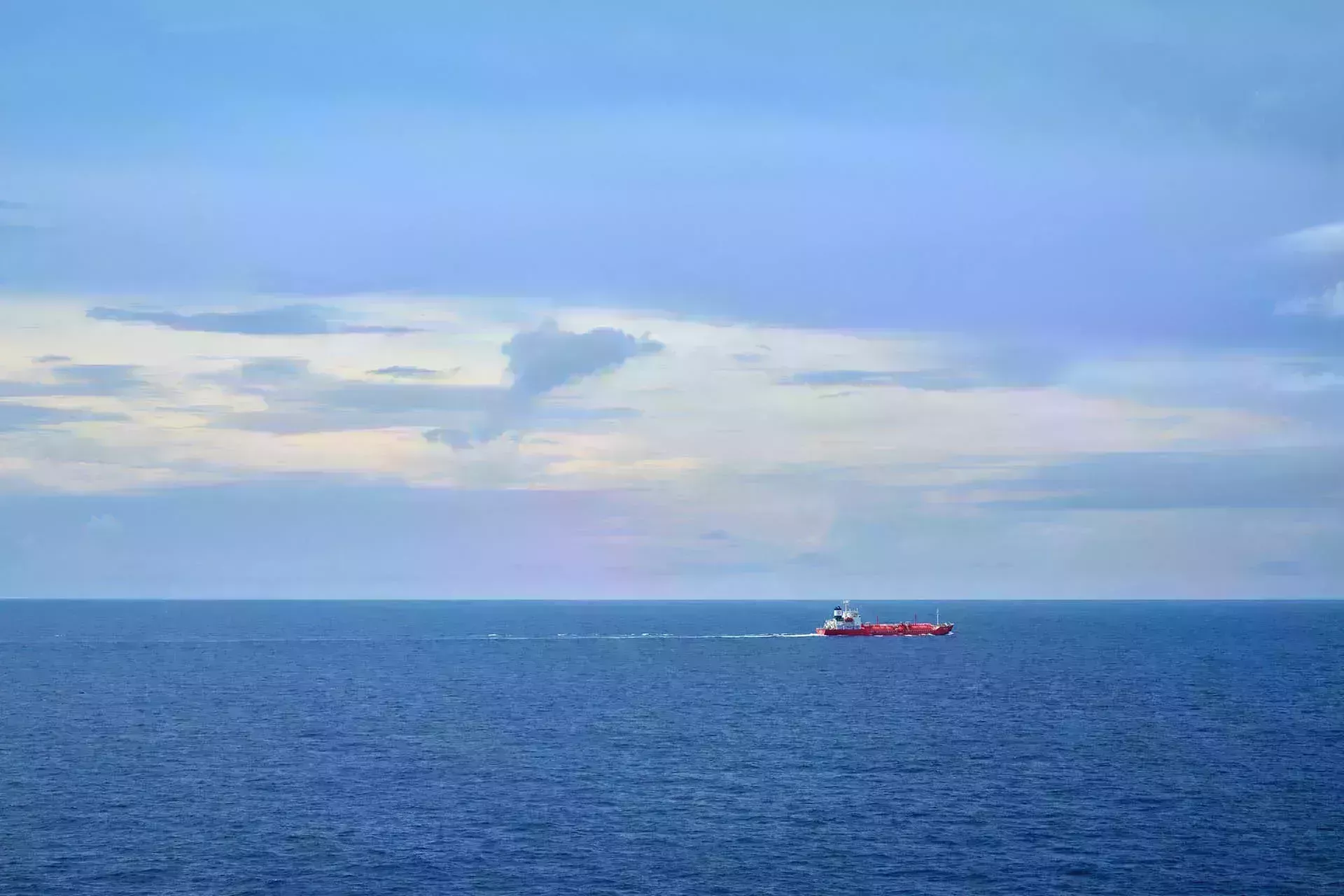 Ship on horizon against pale blue sky