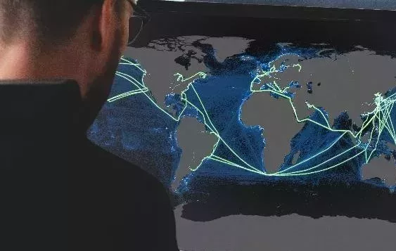 man looking at screen with green shipping routes showing