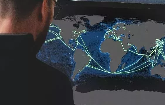 man looking at screen with green shipping routes showing