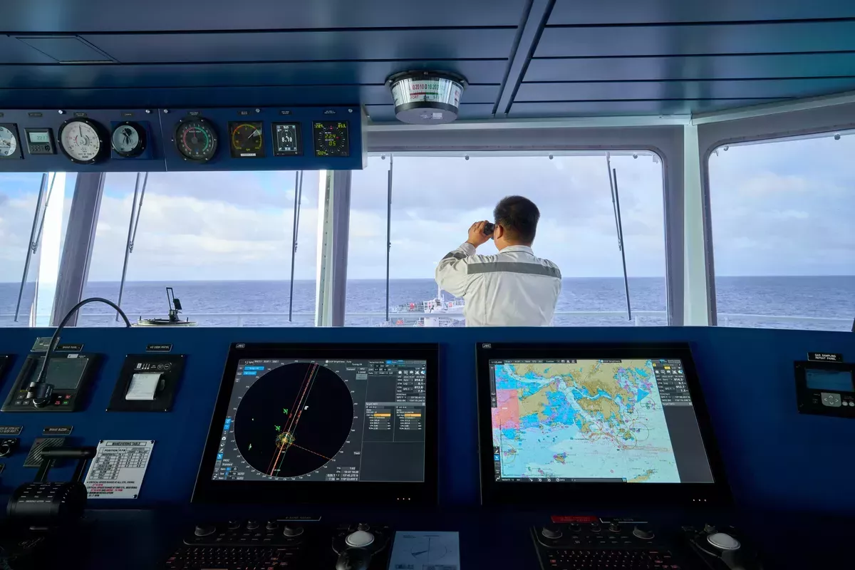 mariner looking out to sea from bridge